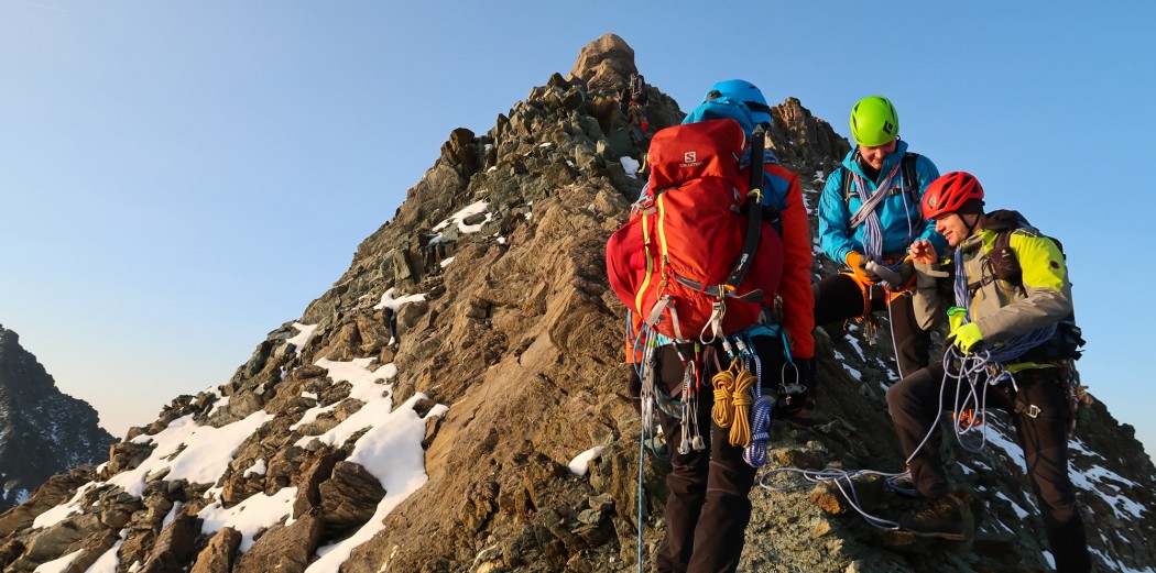 Drei Leute vor einem Berggipfel